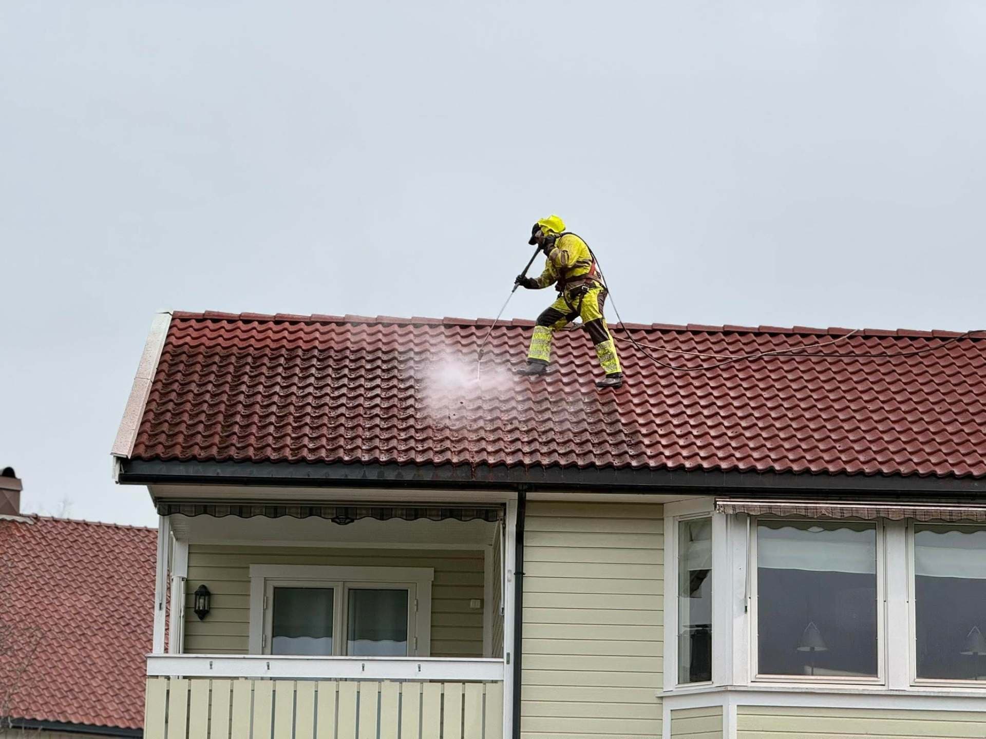 Takvask pågår på rødt tegltak over en veranda i Østfold