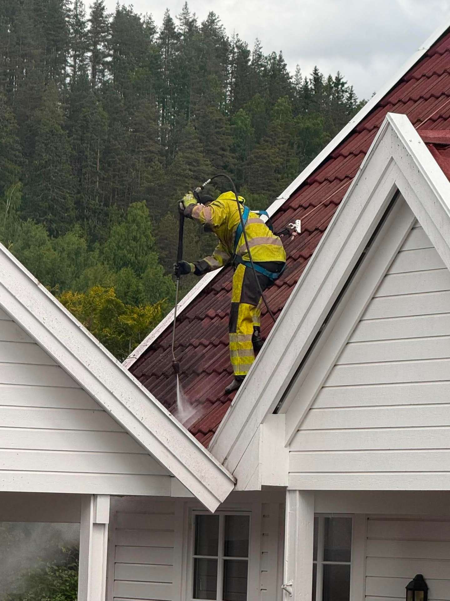 Takvask av rødt tegltak på et hvitt hus i Østfold